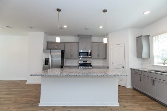 a kitchen with an island with granite counter top and a stainless steel refrigerator
