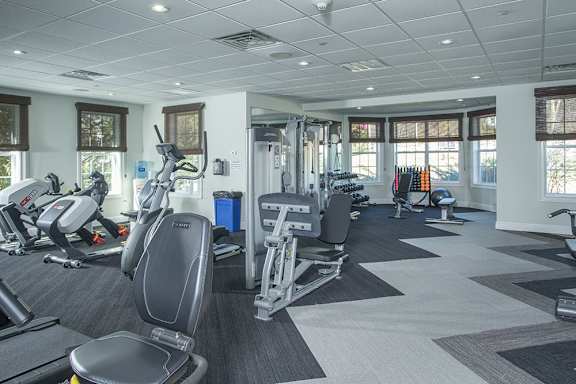 A gym with a variety of equipment including treadmills, stationary bikes, and weight machines.