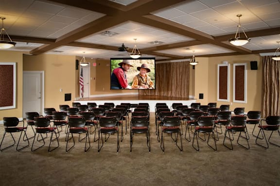 A room with a large screen and chairs facing it.