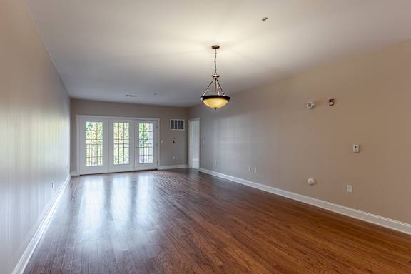 A large empty room with wooden floors and a chandelier hanging from the ceiling.