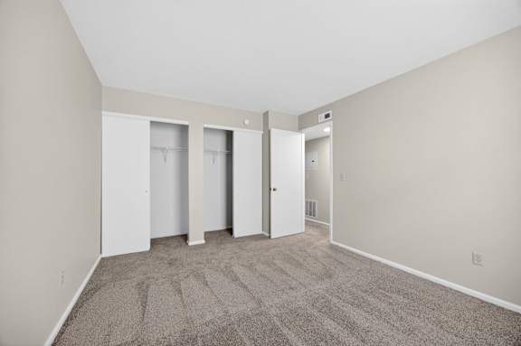A room with a carpeted floor and three white doors.