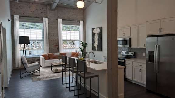 A kitchen with a refrigerator, sink, and a dining table with chairs.