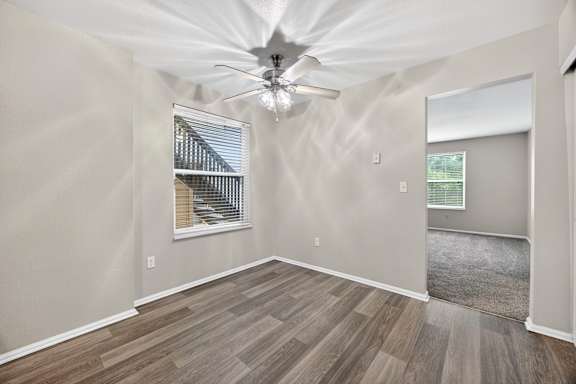 A room with a ceiling fan and a window with blinds.