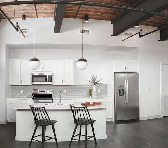 A kitchen with a white counter and black chairs.