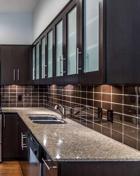 A kitchen with dark brown cabinets and a granite countertop.
