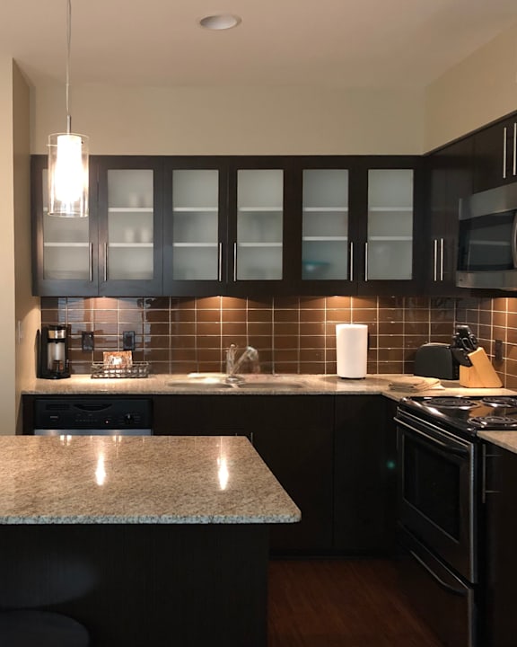 A kitchen with black cabinets and a granite counter.