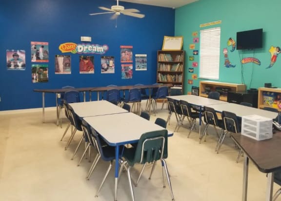 a classroom with desks and chairs in front of a blue wall