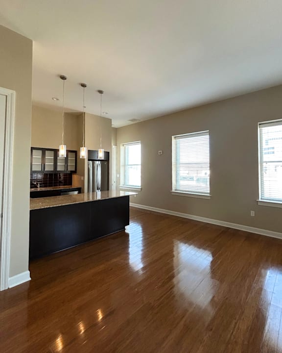 A spacious kitchen with wooden floors and a black countertop.