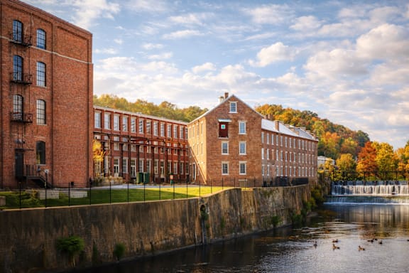 A row of red brick buildings are next to a body of water.