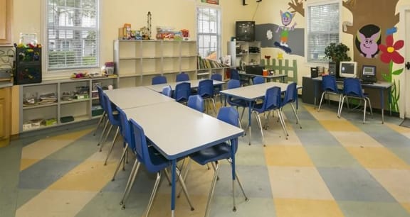 a classroom with white tables and blue chairs and a yellow and gray checkered floor