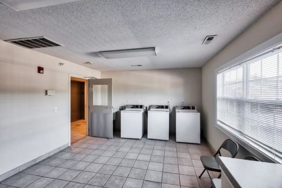 an empty room with four washers and a window