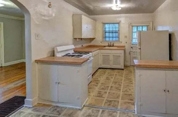 A kitchen with white cabinets and a wooden countertop.