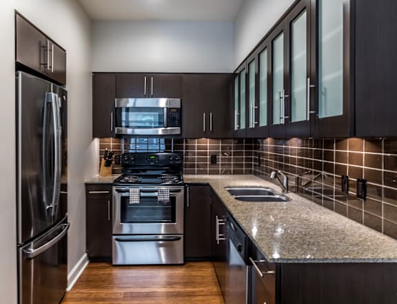 A modern kitchen with dark wood cabinets and stainless steel appliances.