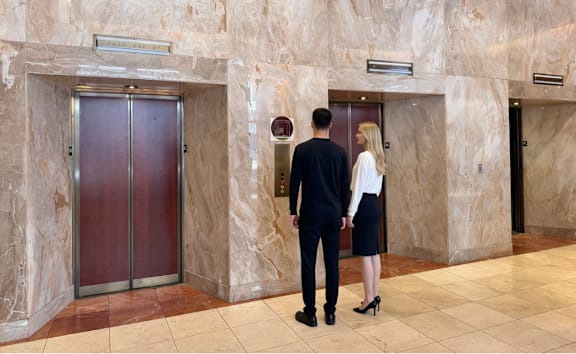 A man and a woman are standing in front of a marble wall.