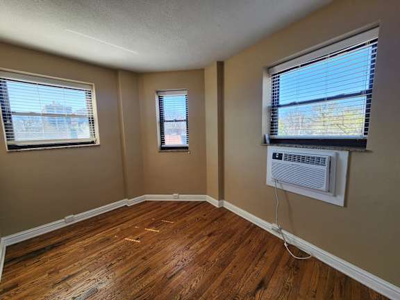 A room with wooden floors and two windows.