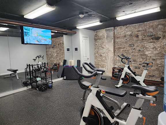 A gym with exercise bikes and a television screen.