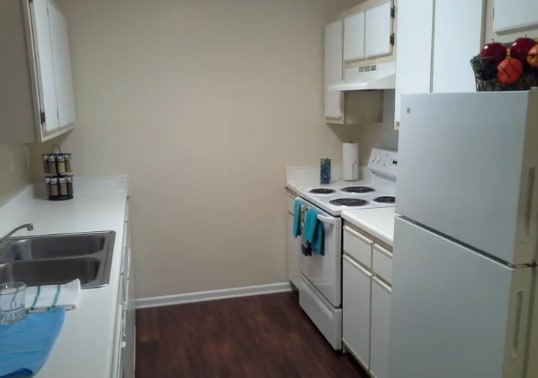 a kitchen with white appliances and a sink and refrigerator