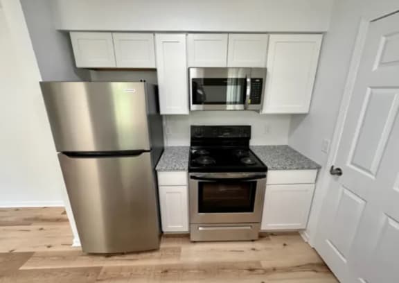 a kitchen with stainless steel appliances and white cabinets at Mammoth at the Orchard Apartments, Arkansas