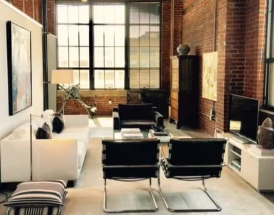the living room of a loft with a white couch and black chairs