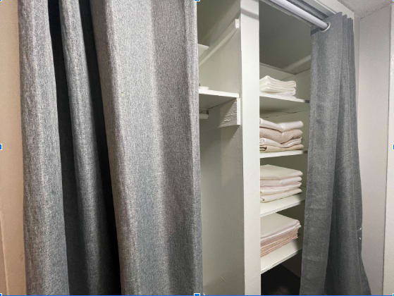 a walk in closet with a curtain and shelves with towels at The Junction, Memphis