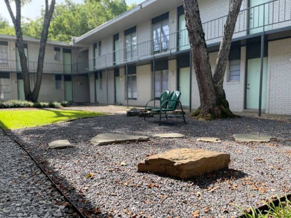 a courtyard with a chair and a tree in front of an apartment building at The Junction, Memphis, TN