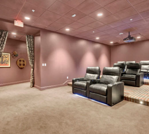 A room with a row of leather chairs and a projector screen.