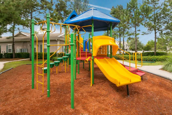 a playground with a yellow slide and red and green chairs