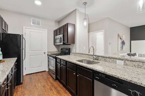 A kitchen with black appliances and granite countertops.