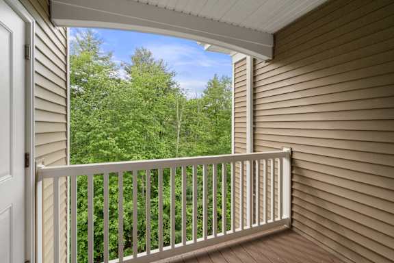 A balcony with a view of trees and sky.