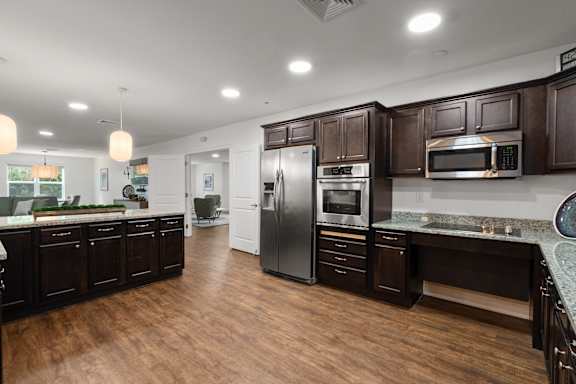 A modern kitchen with dark wood cabinets and stainless steel appliances.