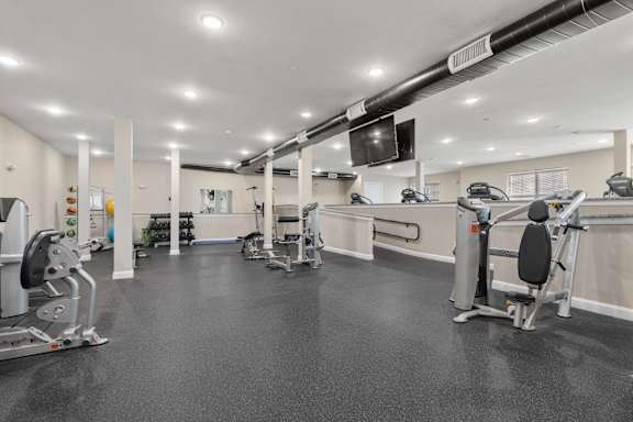 A gym with a variety of equipment including treadmills, weights, and exercise machines.