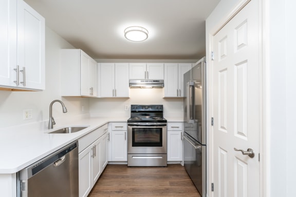 a white kitchen with stainless steel appliances and white cabinets