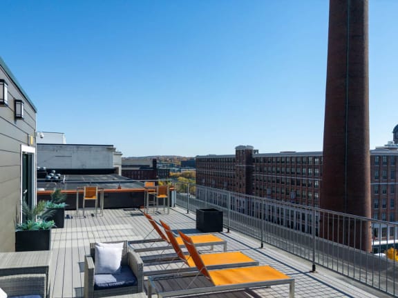 a communal roof deck with lounge chairs and a view of the city