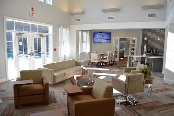 A large room with a couch, chairs, and a television.
