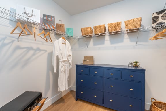Large closet with a blue dresser and a white robe hanging on a rack above
