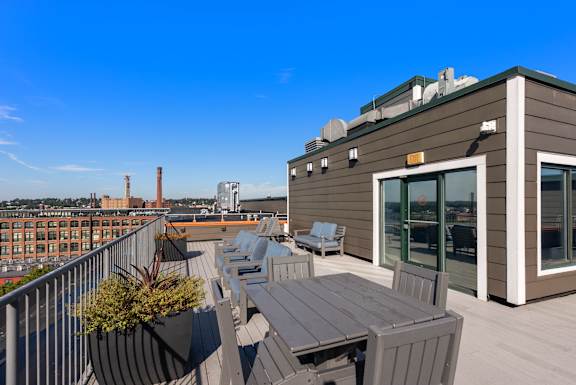 A rooftop patio with a table and chairs overlooking a cityscape.