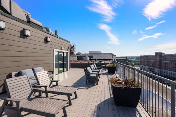 A balcony with chairs and a table overlooking a cityscape.
