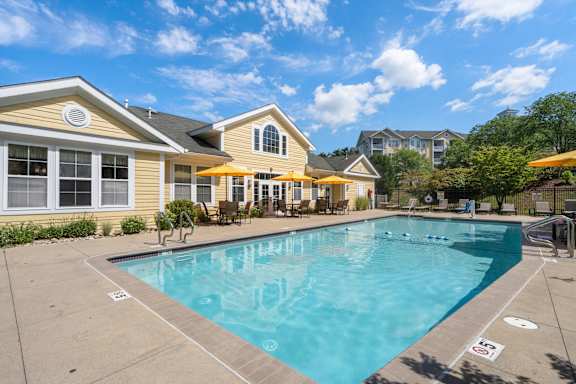 A swimming pool in front of a yellow house.