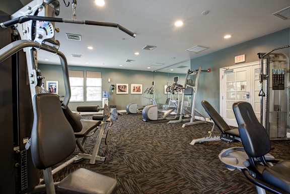 A gym with a variety of equipment including treadmills, weights, and exercise machines.