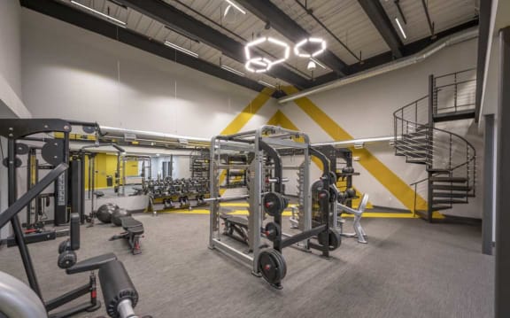 a spacious fitness center with weights and cardio equipment and a spiral staircase