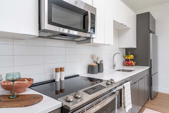 A modern kitchen with a stainless steel refrigerator and a microwave above the stove.
