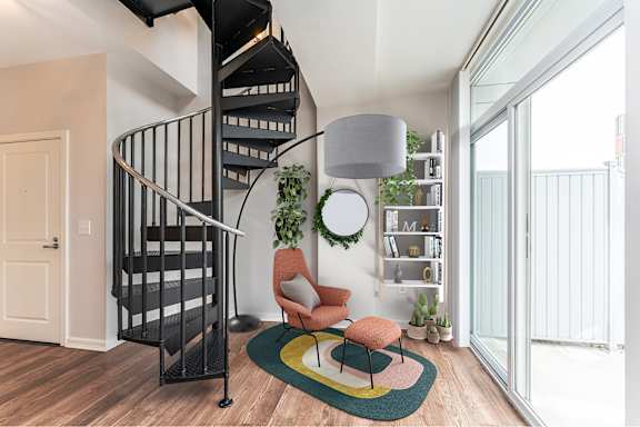 A woman is sitting on a chair in a room with a spiral staircase.