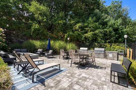 A patio with a table and chairs surrounded by greenery.