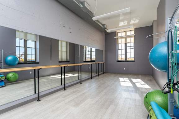 A gym with a row of windows and exercise balls.