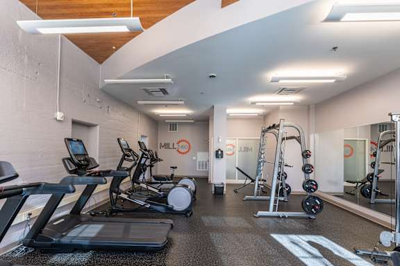 A gym with treadmills, elliptical machines, and weights.