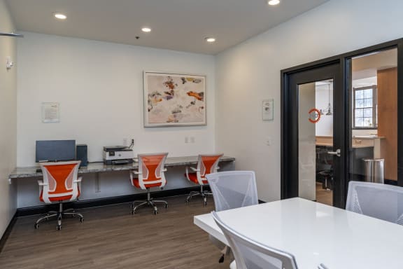 a conference room with a white table and chairs, printer, a desk with a computer