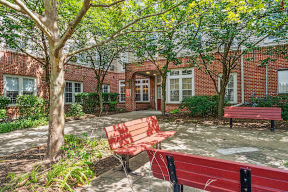 A red bench sits in front of a building with a tree in front of it at Monterey Place, New Haven, 06511