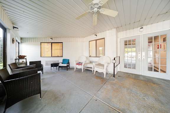 A patio with a white ceiling and a fan.