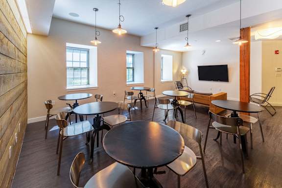 a dining room with tables and chairs and a tv at Ames Shovel Works Apartments, Massachusetts, 02356