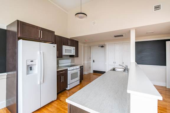 a renovated kitchen with white appliances and dark wood cabinets at Beverly Village for Living & the Arts Apartments, Beverly, 01915